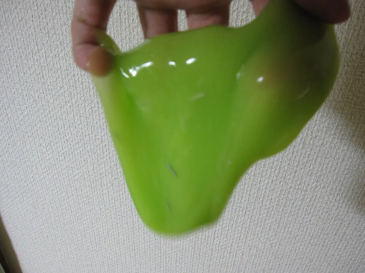Mão de adulto segurando uma porção de slime verde